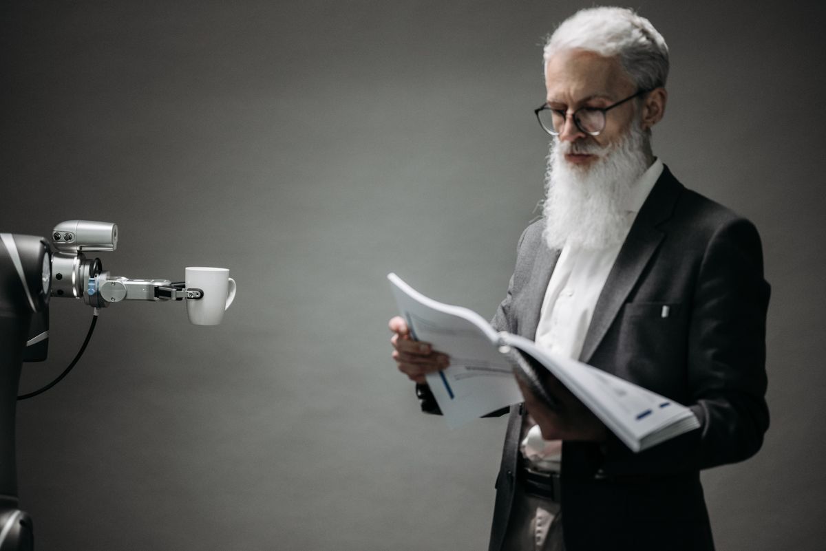 Robotarm rækker en kop kaffe til en ældre mand, der læser